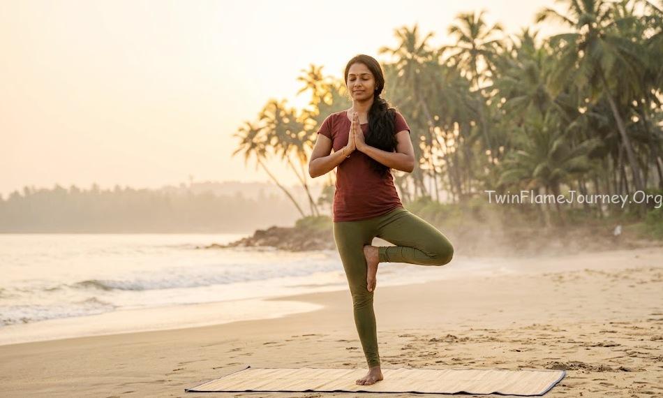 South Indian woman practicing yoga at Kerala beach during sunrise.