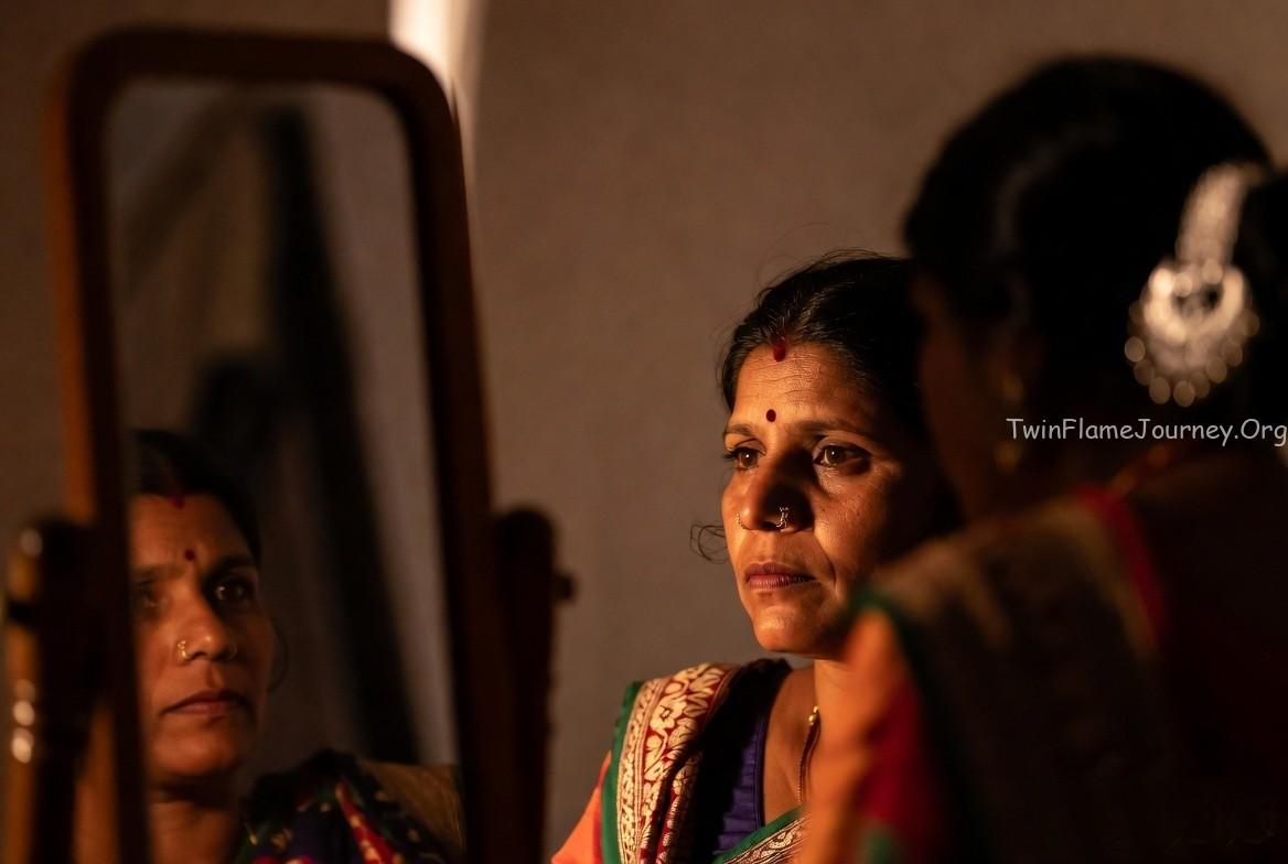 DF with traditional attire, reflecting deeply while looking into a mirror, symbolizing soul recognition.