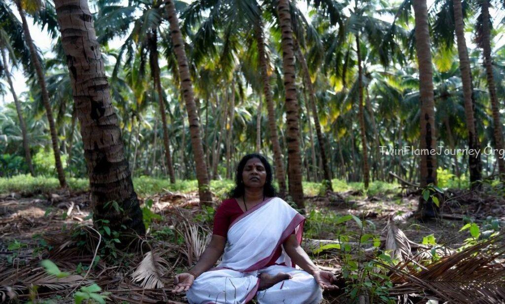 Young South Indian woman meditating in a lush green Kerala landscape